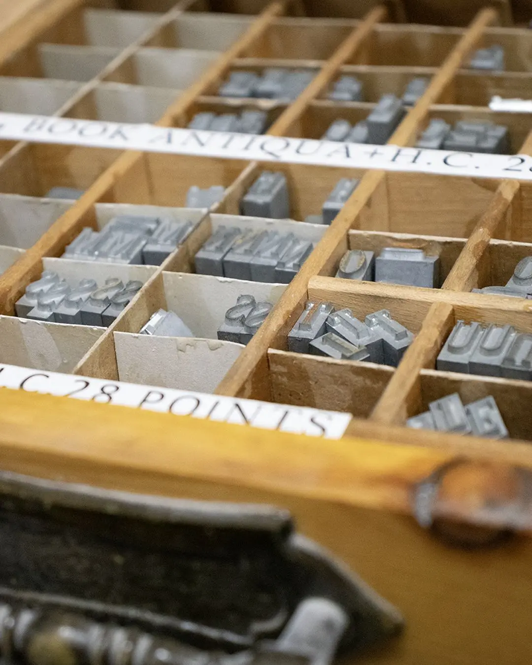Close-up of lead letters in the compartments of a type case.