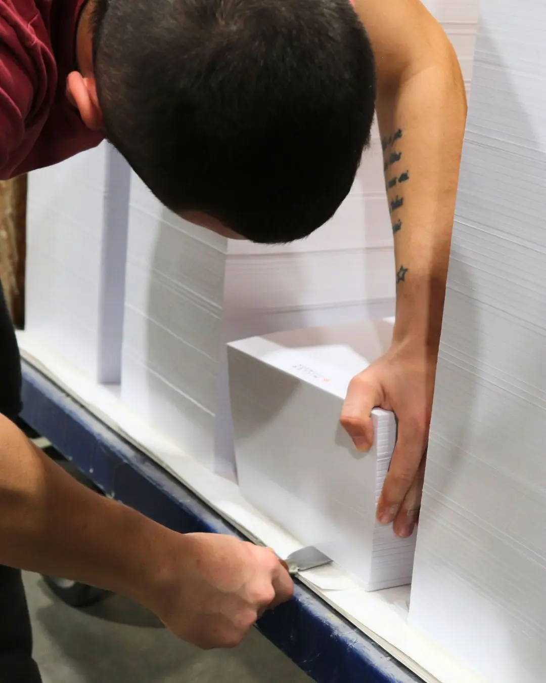 An employee prepares a stack of white sheets.