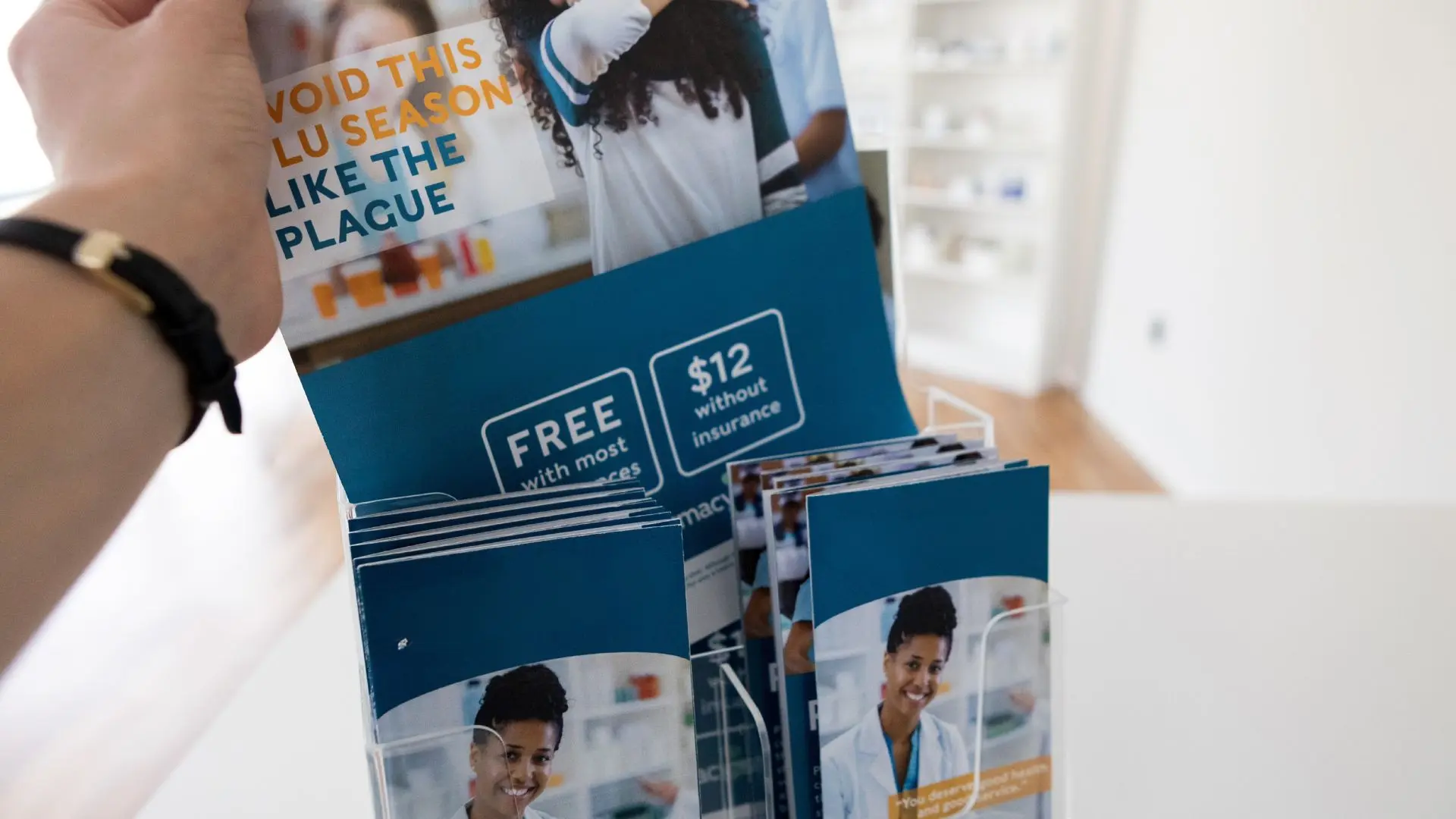 A hand picks a brochure from a display rack